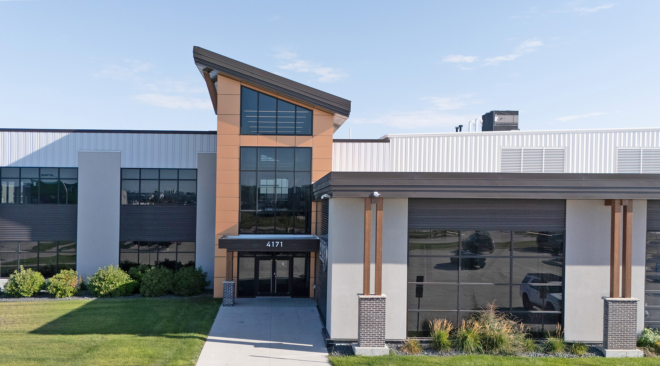 Modern industrial fitness training space with weight racks, cardio equipment, and mezzanine level in a large open warehouse interior.