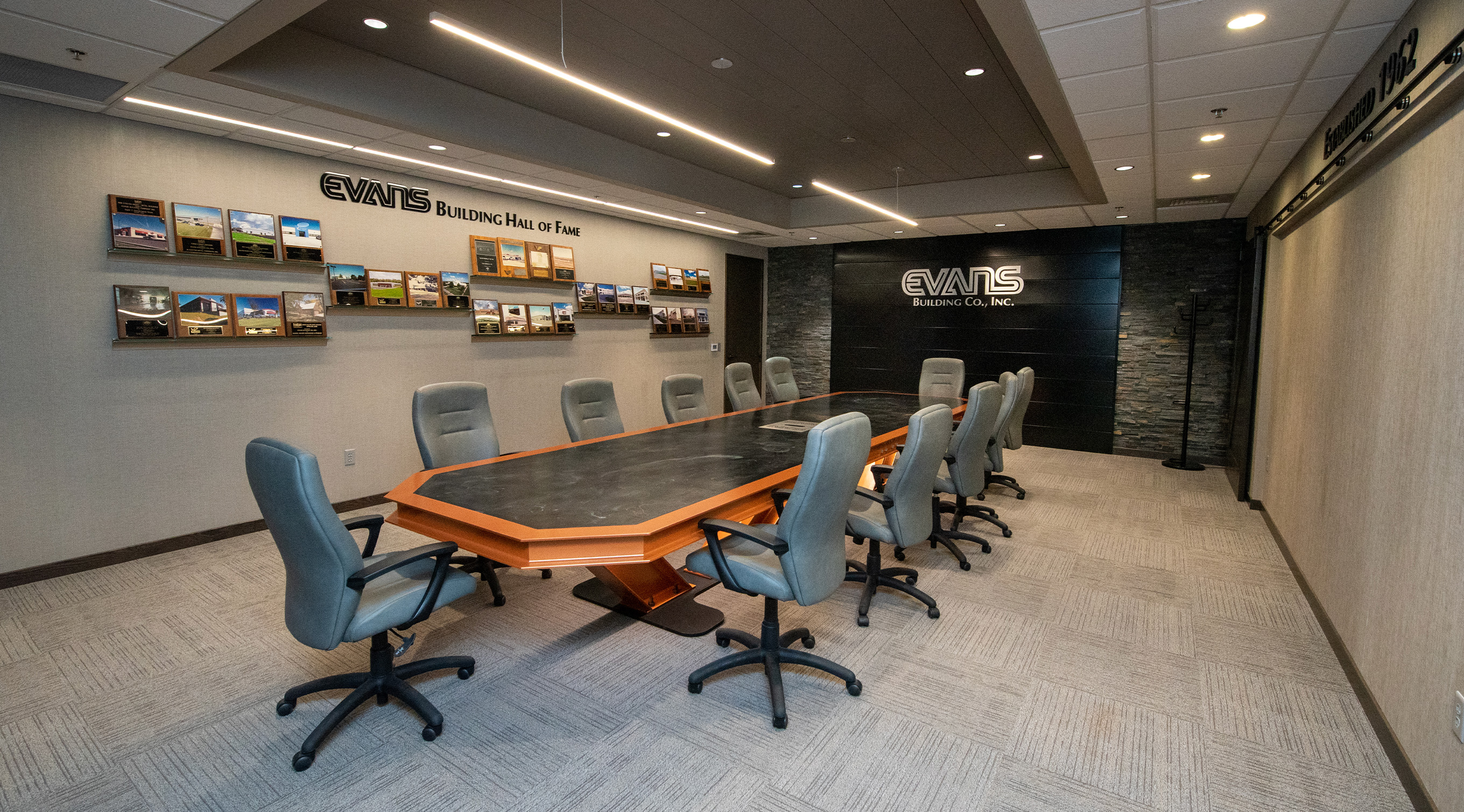 Modern commercial building lobby with glass walls, reception desk, and staircase.