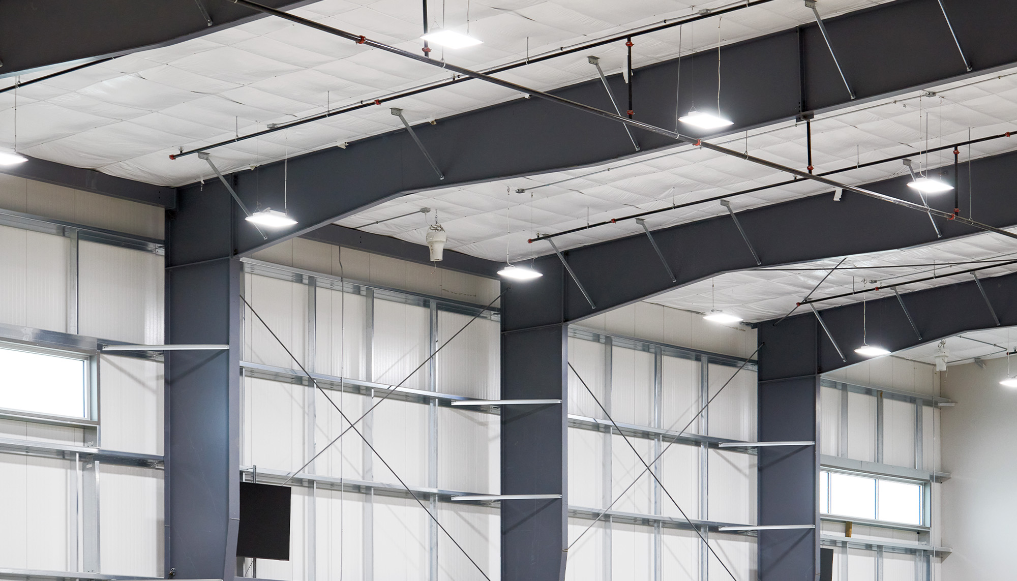 Industrial interior with exposed steel framing, cross bracing and high-bay insulated wall systems designed for large-scale operational space.