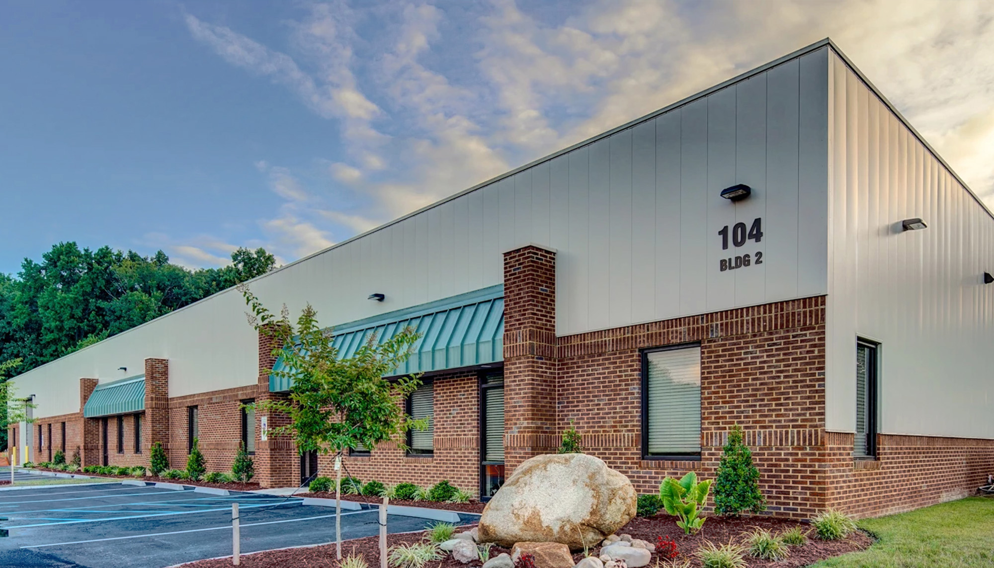 Modern commercial metal building with brick and white panel exterior under a cloudy sky.