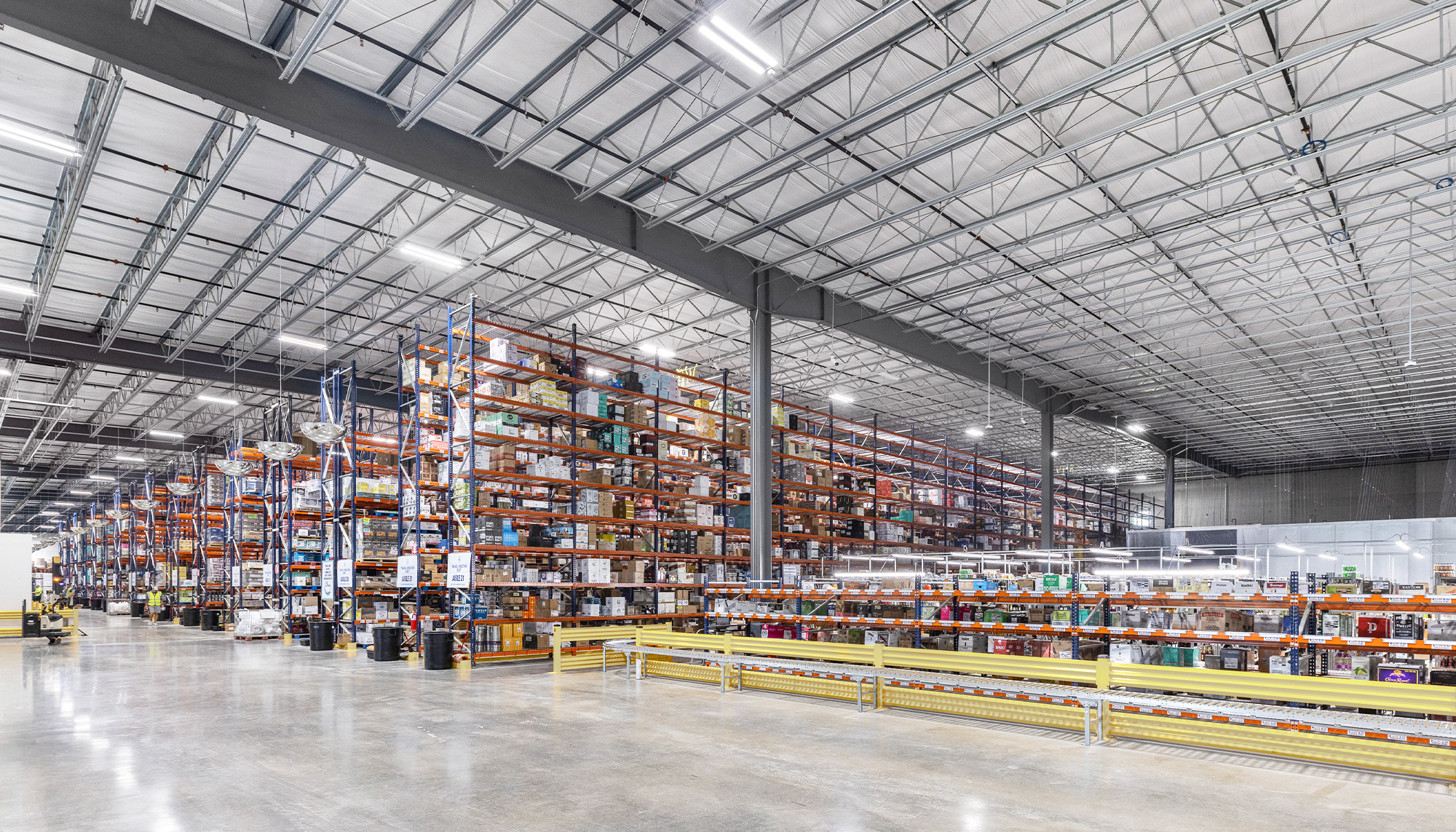 Large-scale distribution warehouse with tall pallet racking, exposed steel ceiling structure and polished concrete floors supporting high-volume storage operations.