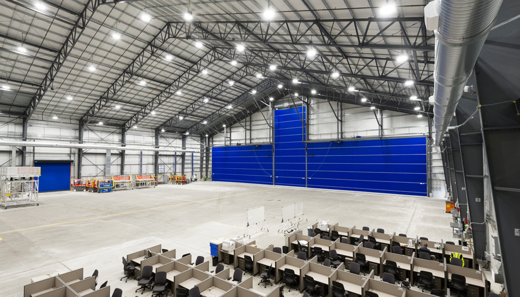 Large industrial event and operations space with exposed steel framing, high-bay ceiling structure and flexible open floor layout with integrated seating areas.