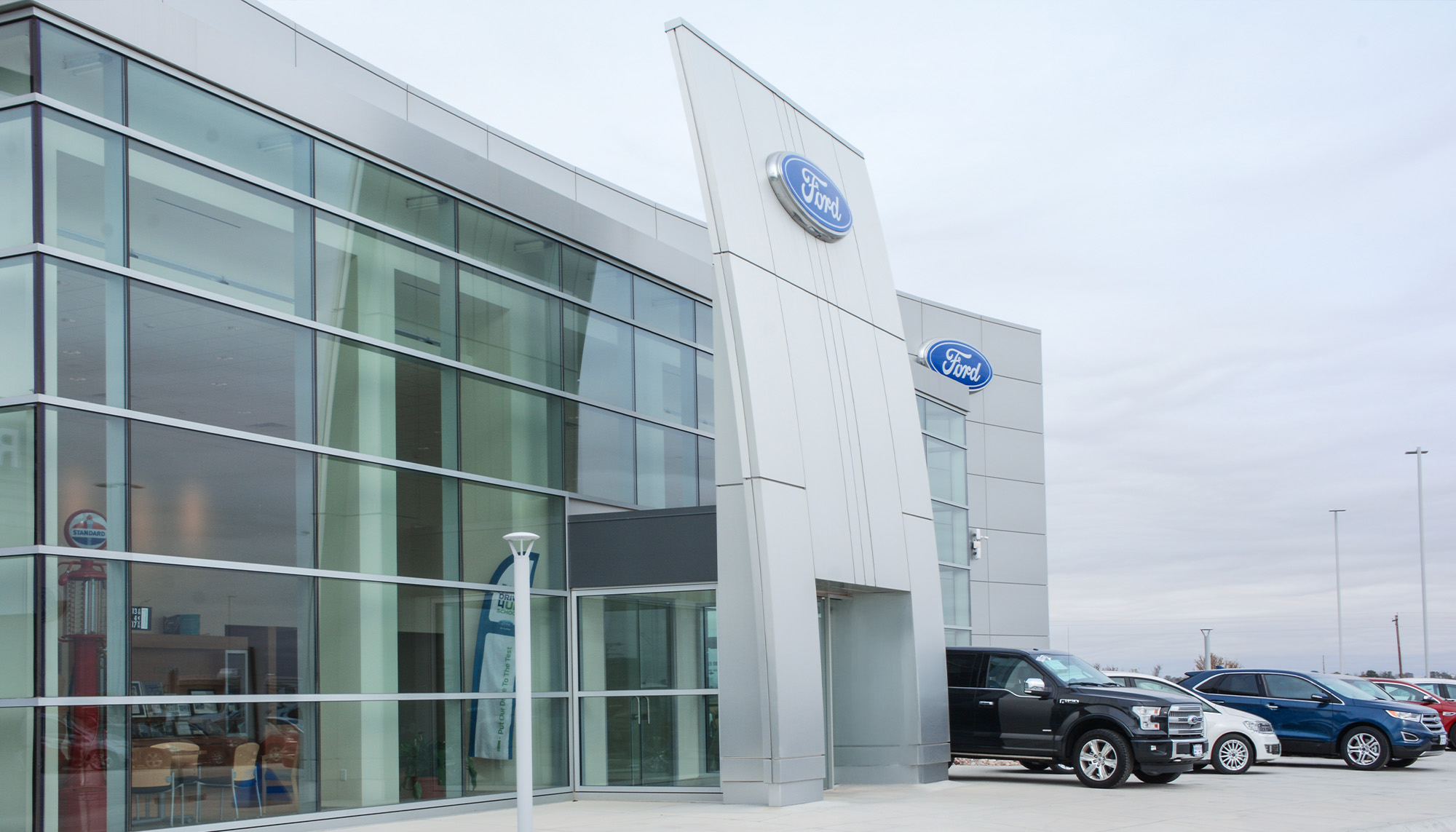 Automotive dealership exterior with architectural metal wall panels, glass curtain wall system and commercial steel building construction.