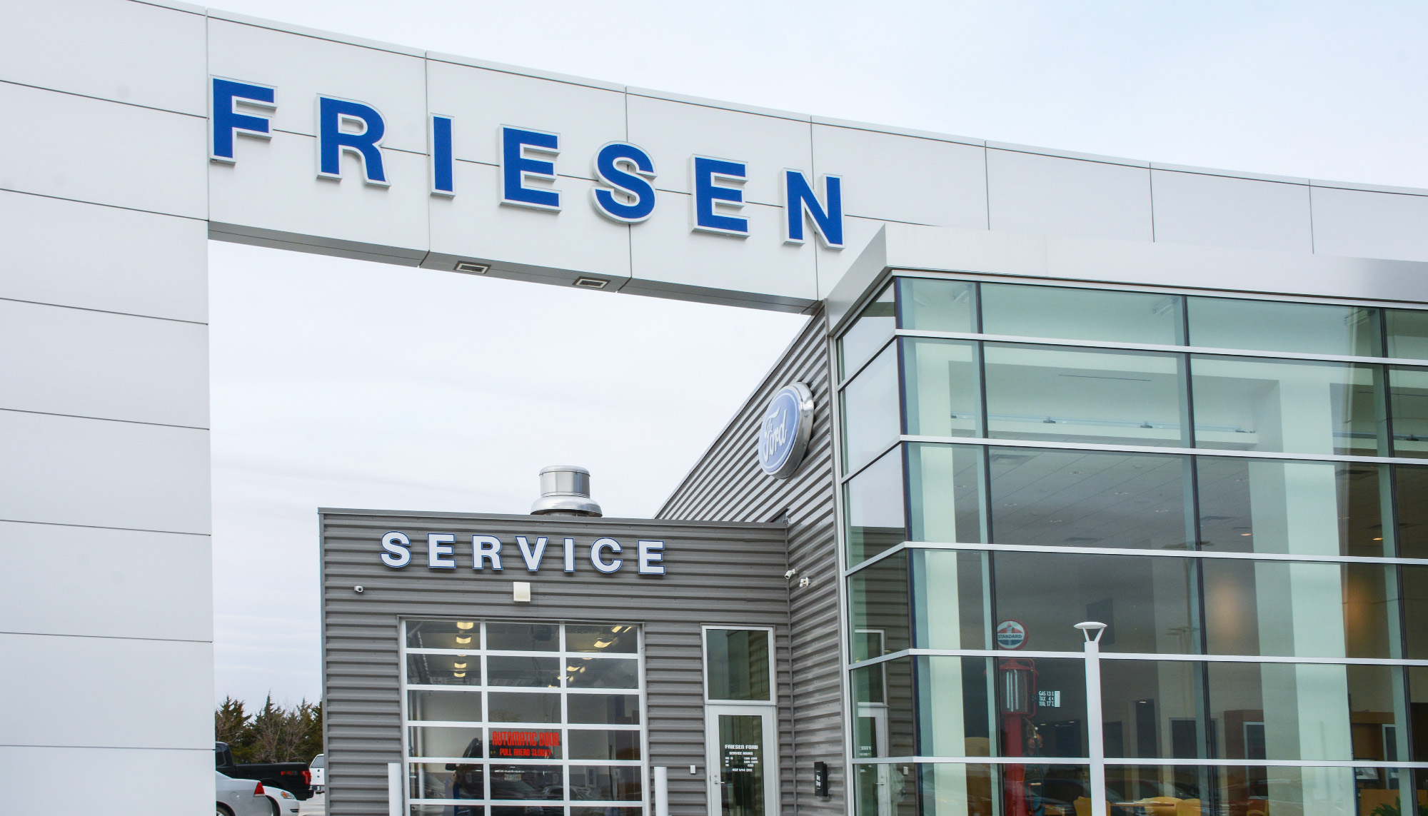 Modern automotive dealership service center with metal wall panels, glazed storefront system and commercial steel building facade.