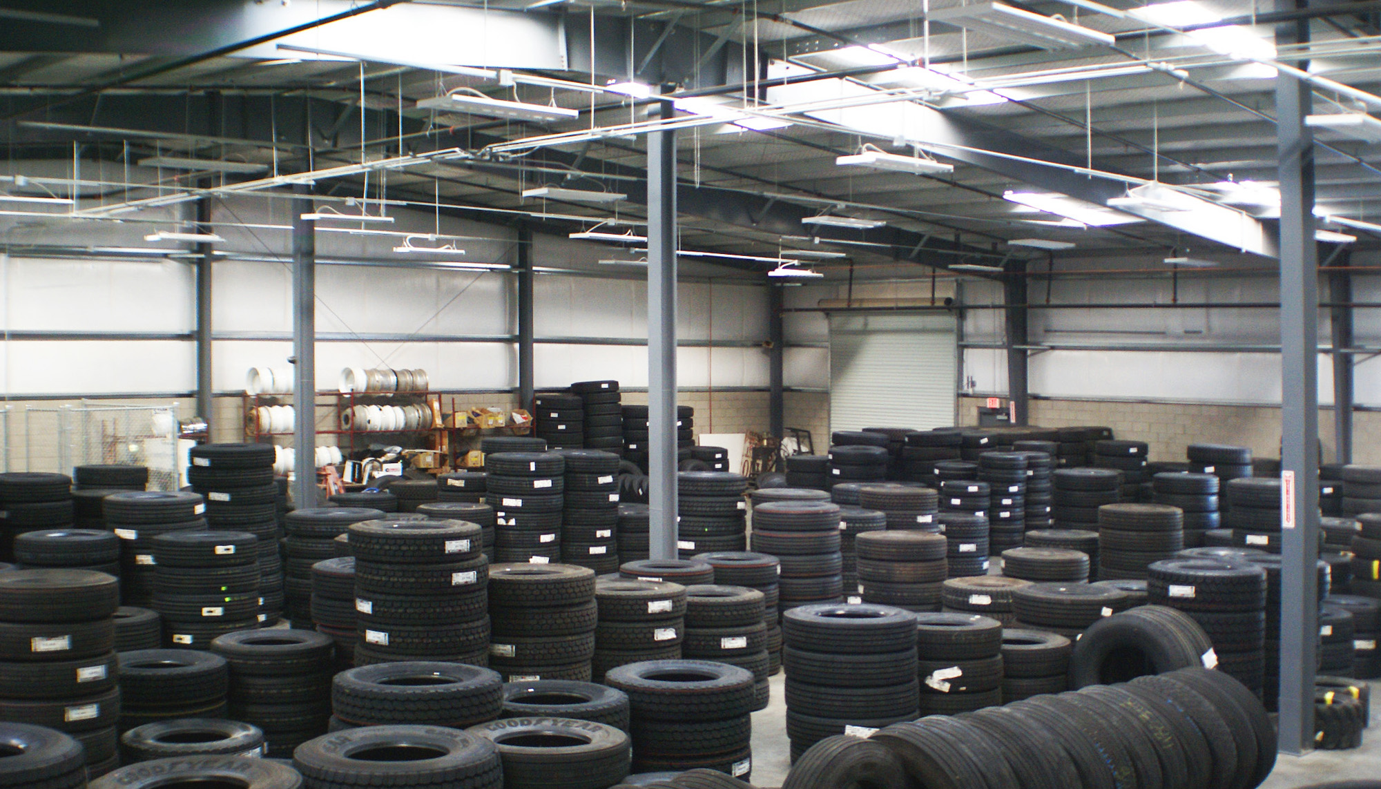 Interior of a steel-framed warehouse building with stacked tire inventory, rigid frame columns and high-bay industrial storage space.