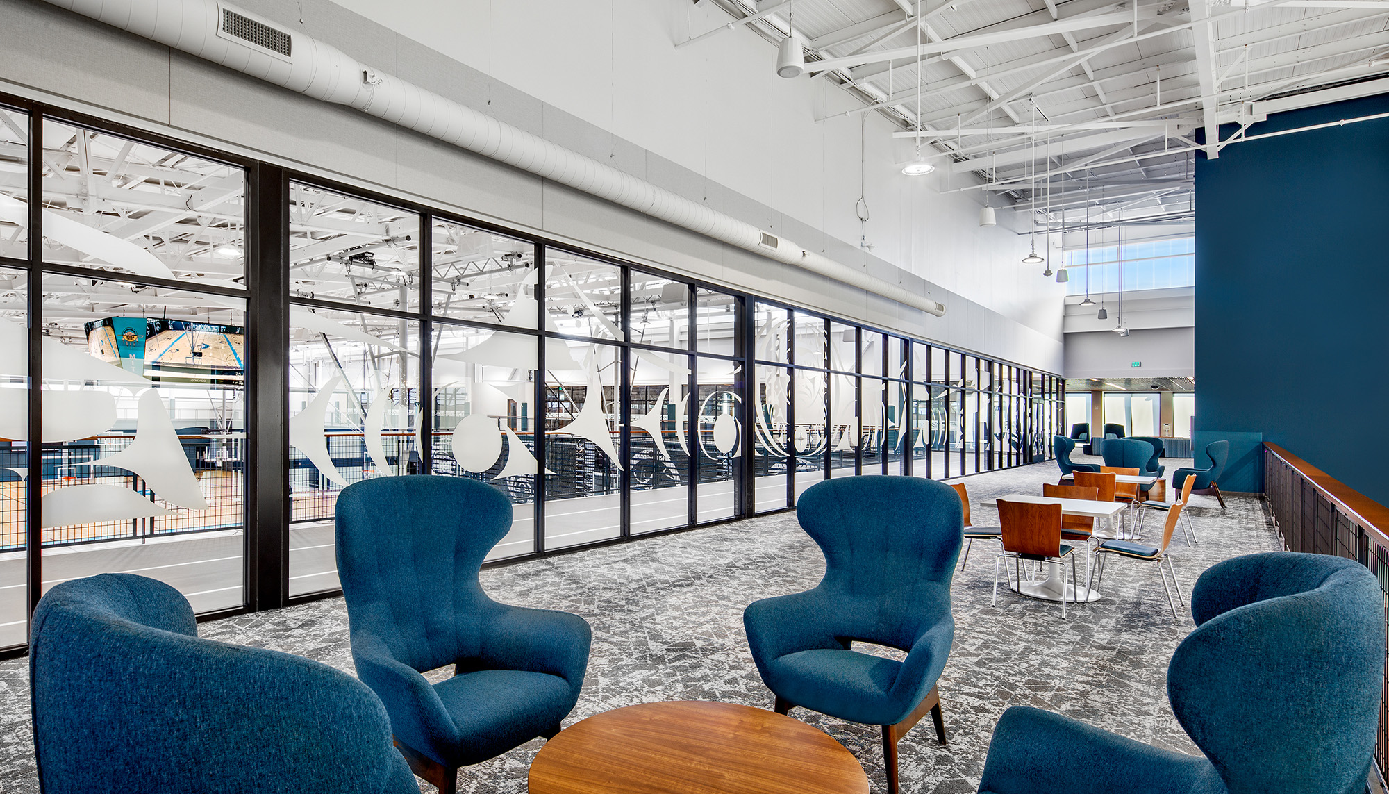 Recreation center lounge overlooking indoor aquatic facility with structural steel framing and modern community building design.