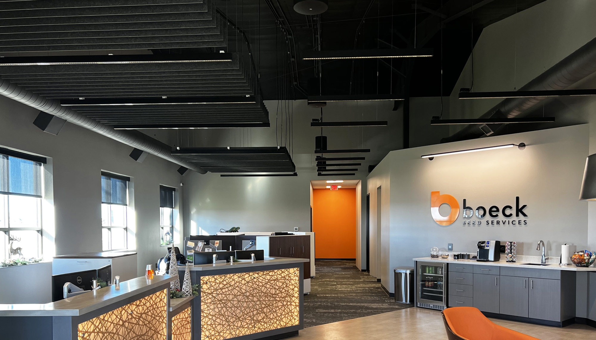 Modern office interior featuring exposed ceilings, integrated lighting and collaborative reception workspace.