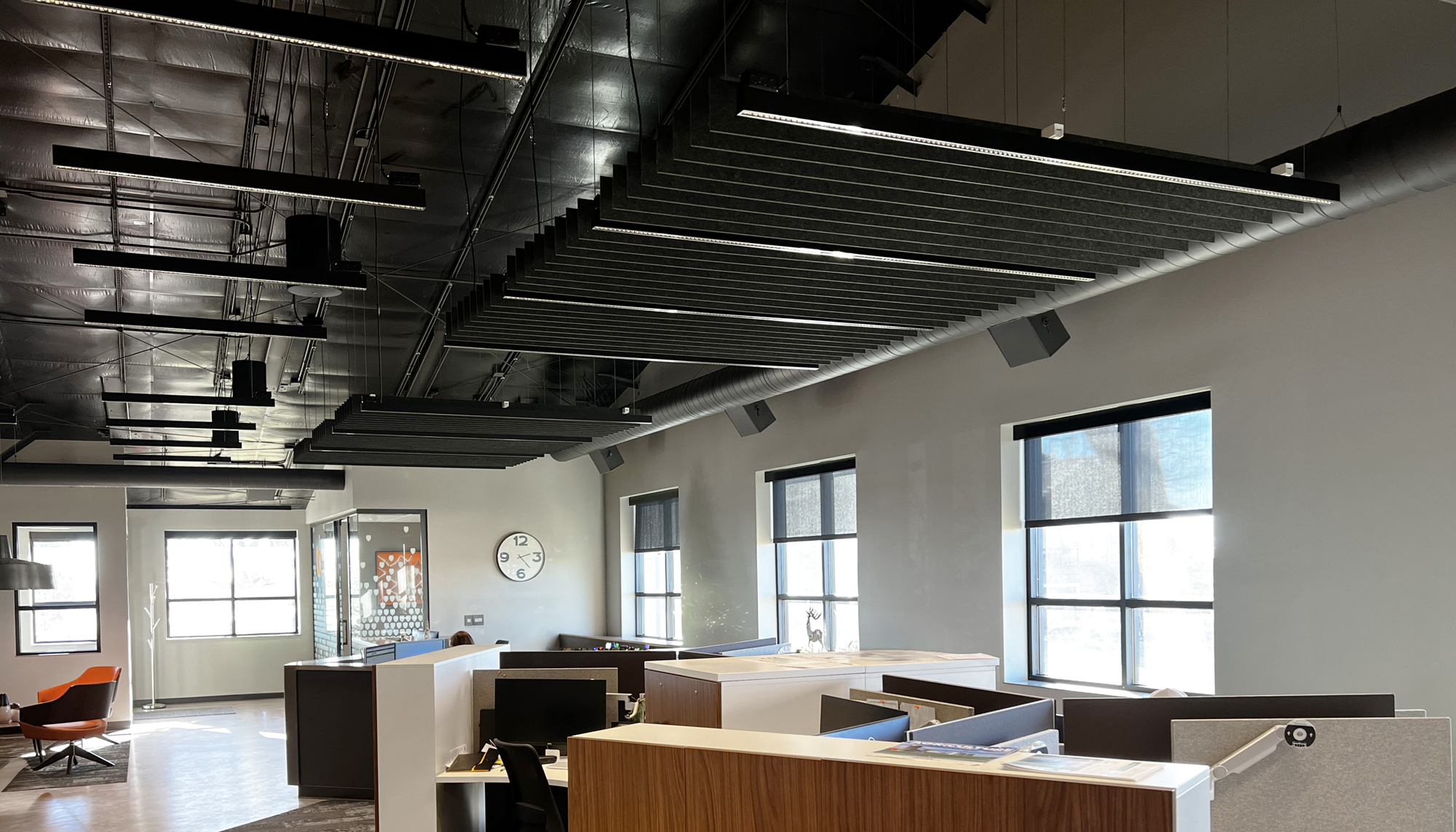 Open office workspace featuring exposed ceilings, acoustic baffles and modern workstation layout.