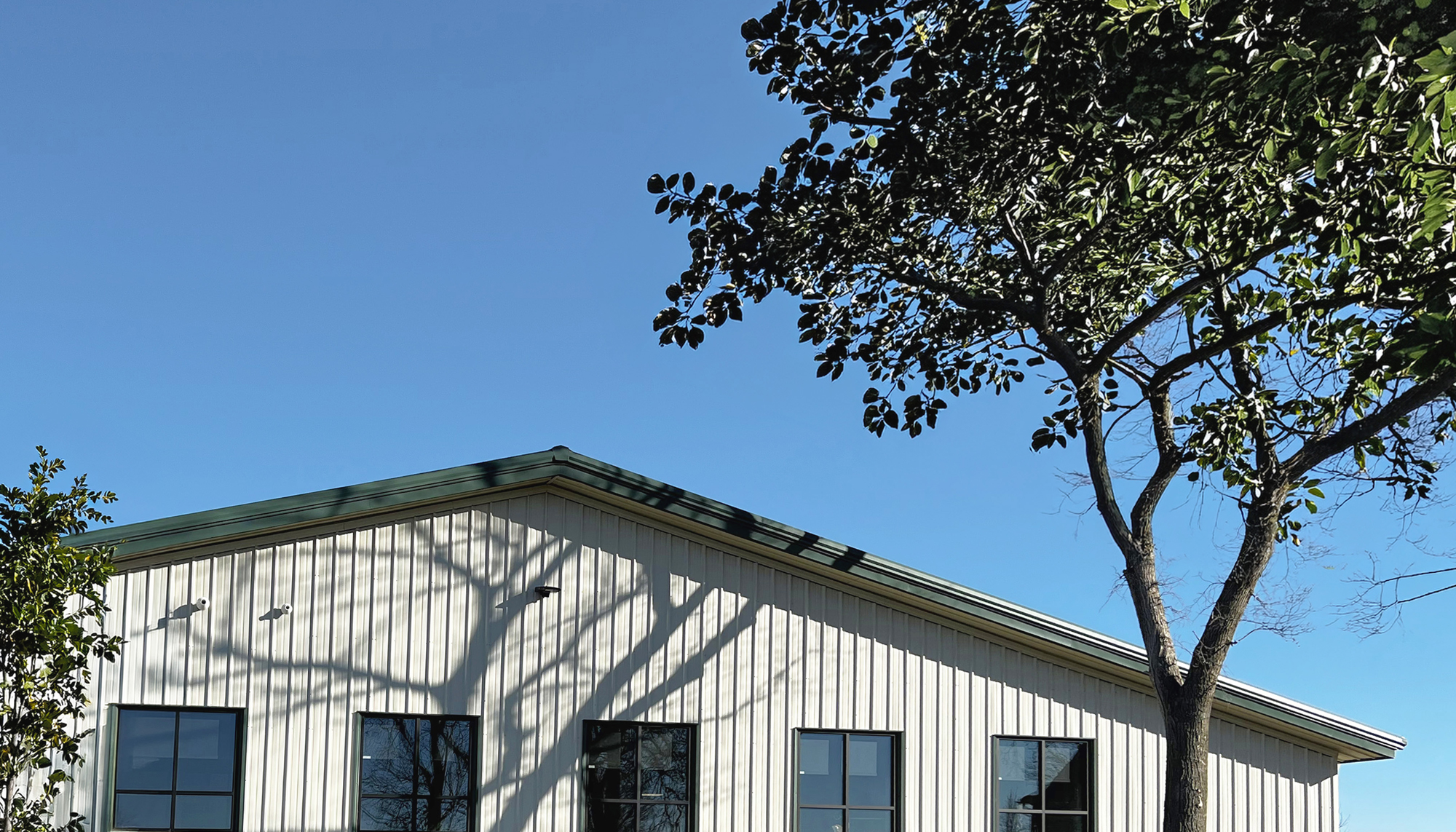 Pre-engineered metal building exterior with vertical wall panels, dark-framed windows and integrated landscape design.