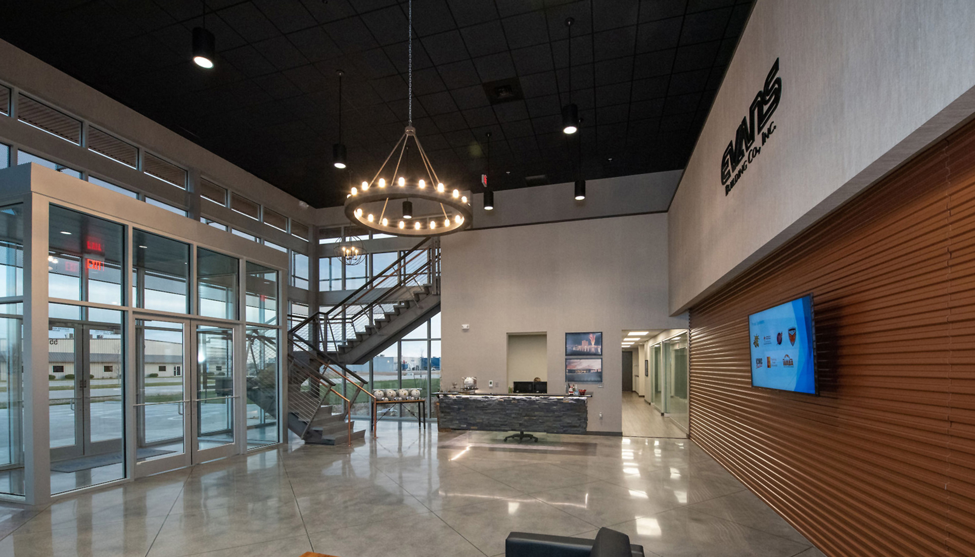 Lobby interior at the Evans Building Company headquarters featuring glass office fronts, exposed staircase and integrated architectural finishes.