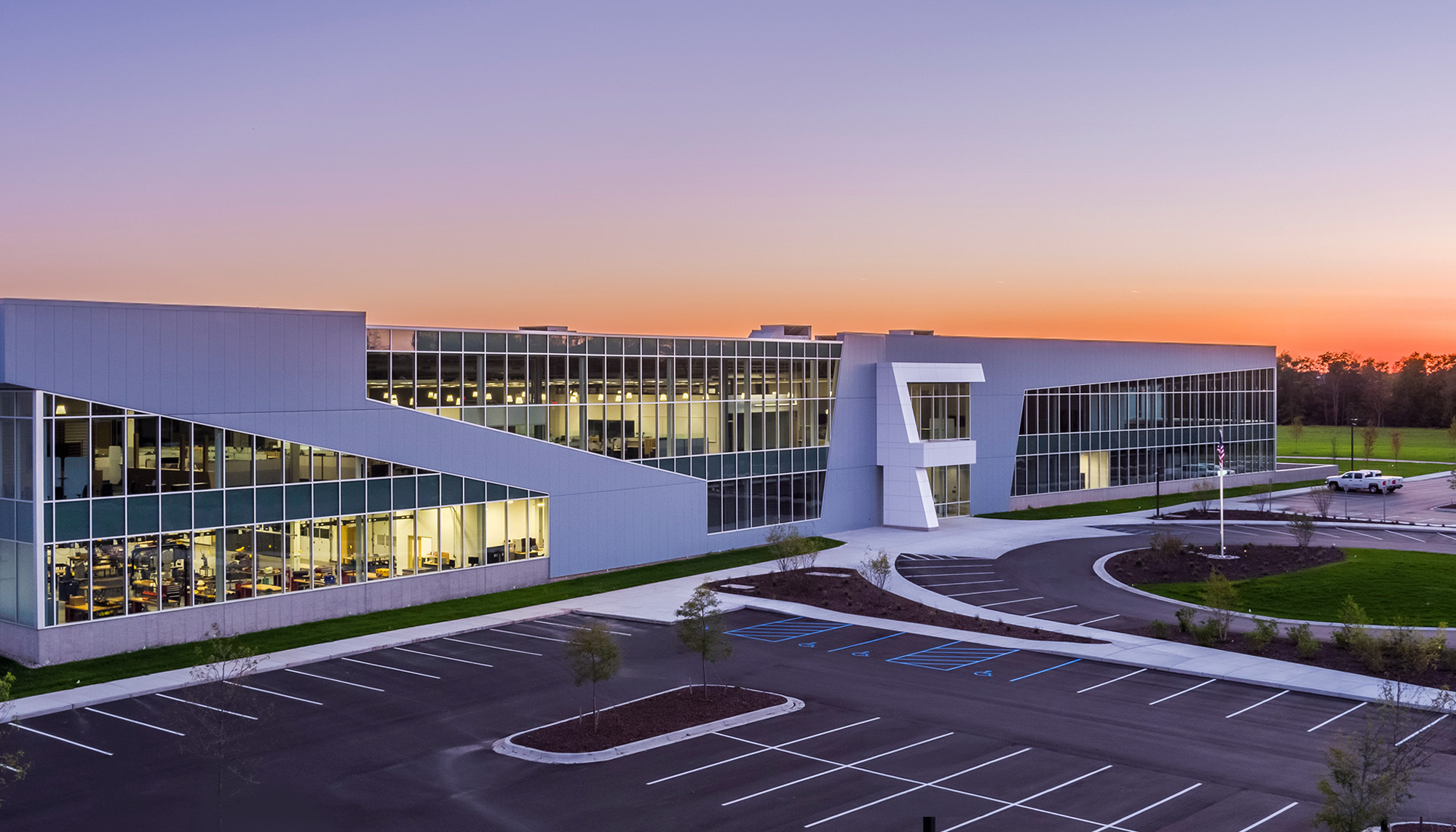 Corporate headquarters facility featuring curtain wall glazing, architectural metal wall panels and large-scale steel building construction at dusk.