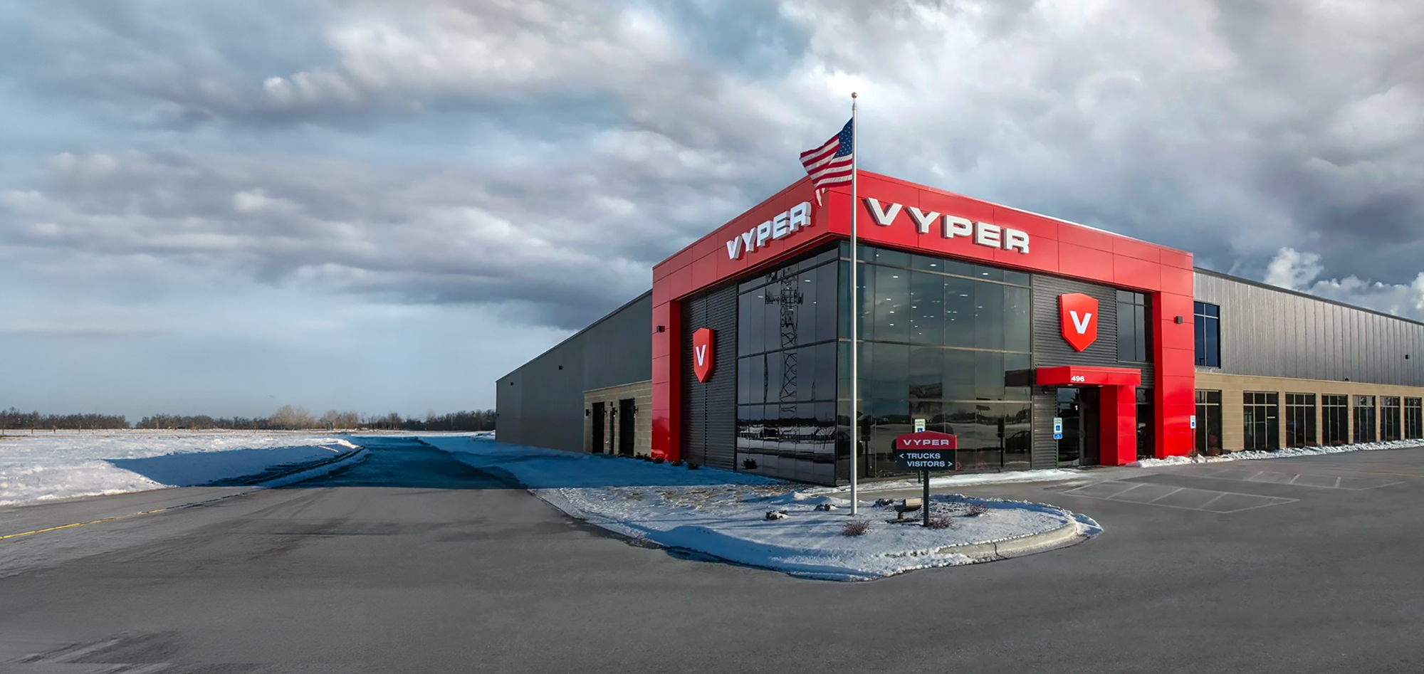 Modern gray commercial building with bold red VYPER branding, large glass windows and snow-covered landscaping under a cloudy sky. Vyper industrial headquarters.