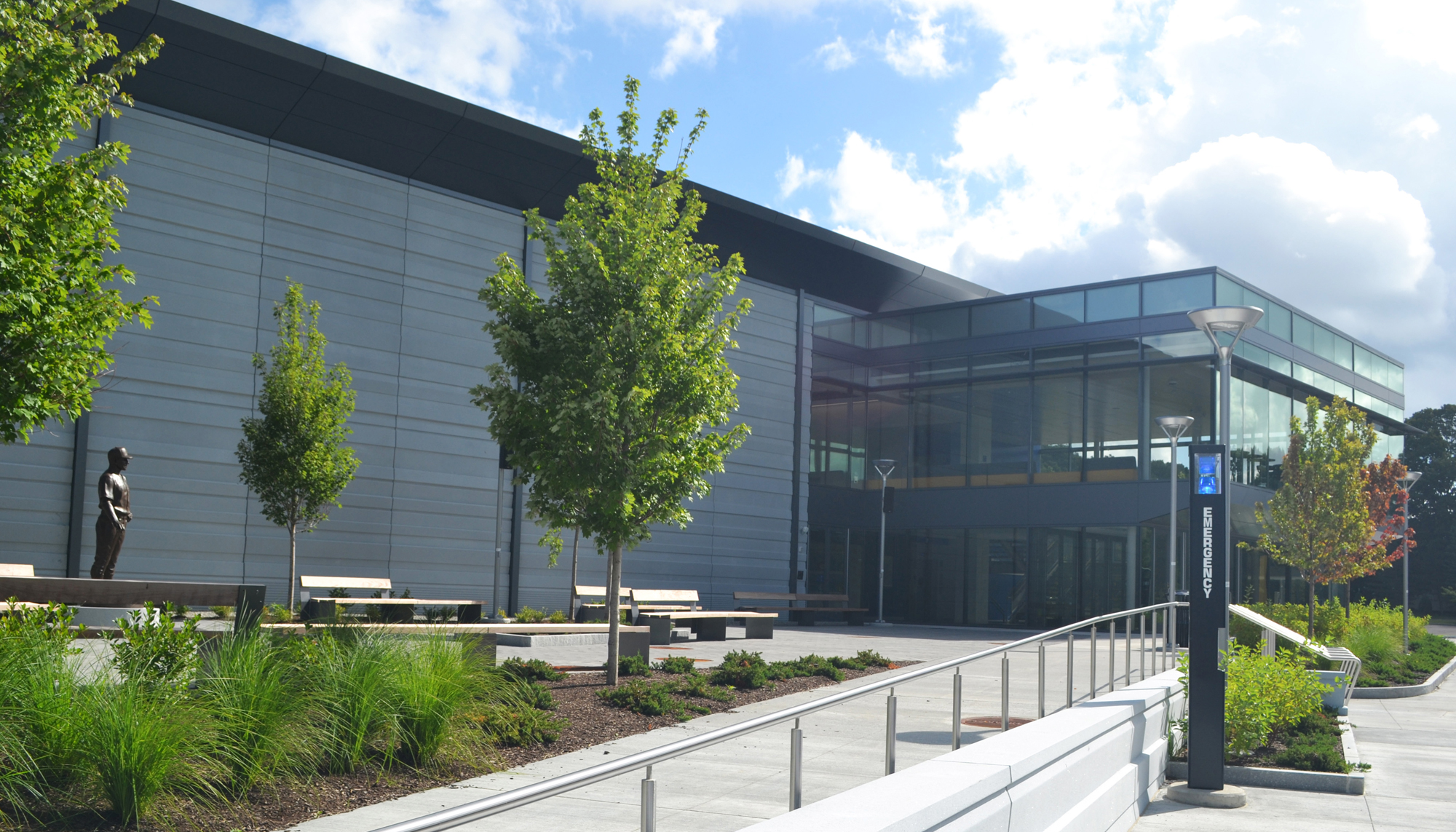 Entrance view of Bentley University’s Sports and Recreation facility with landscaped pedestrian access and modern glass facade.