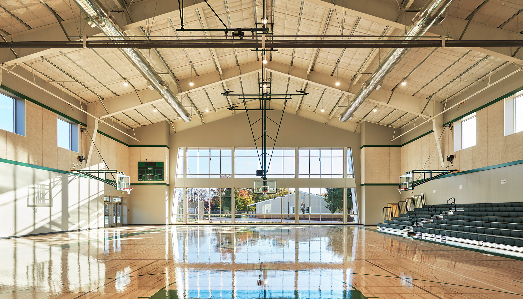 Indoor gymnasium featuring clear span steel framing, hardwood basketball court and multi-purpose recreation facility design.