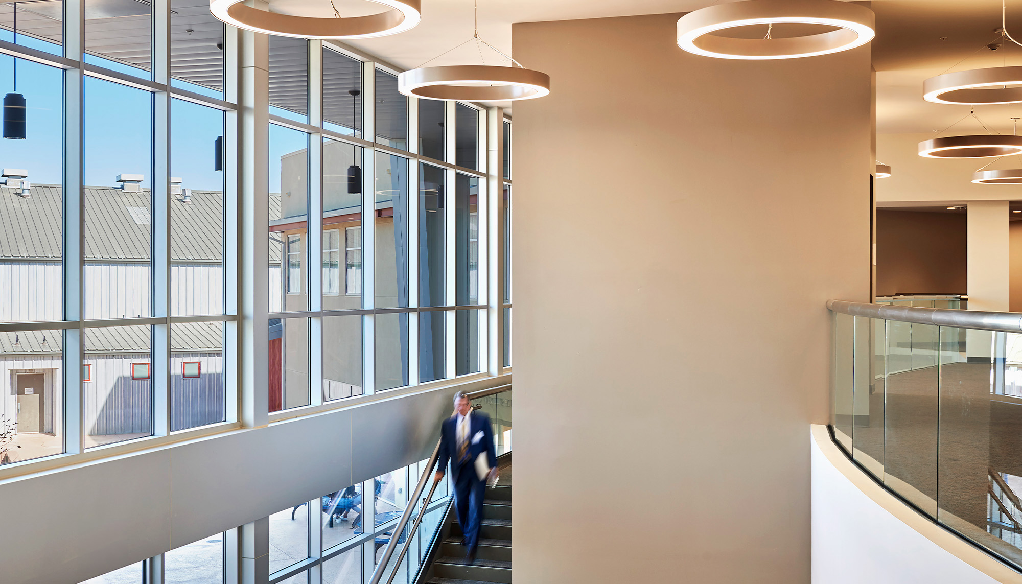 School recreation center interior featuring curtain wall glazing, open mezzanine design and modern steel building construction.