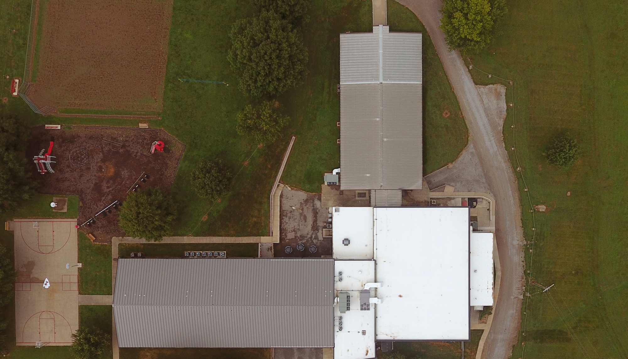 Top aerial view of the Santa Fe Schools Roof Retrofit project featuring coordinated roofing systems across multiple educational building sections designed to improve facility protection, adapt to varied existing conditions and maintain uninterrupted school operations.