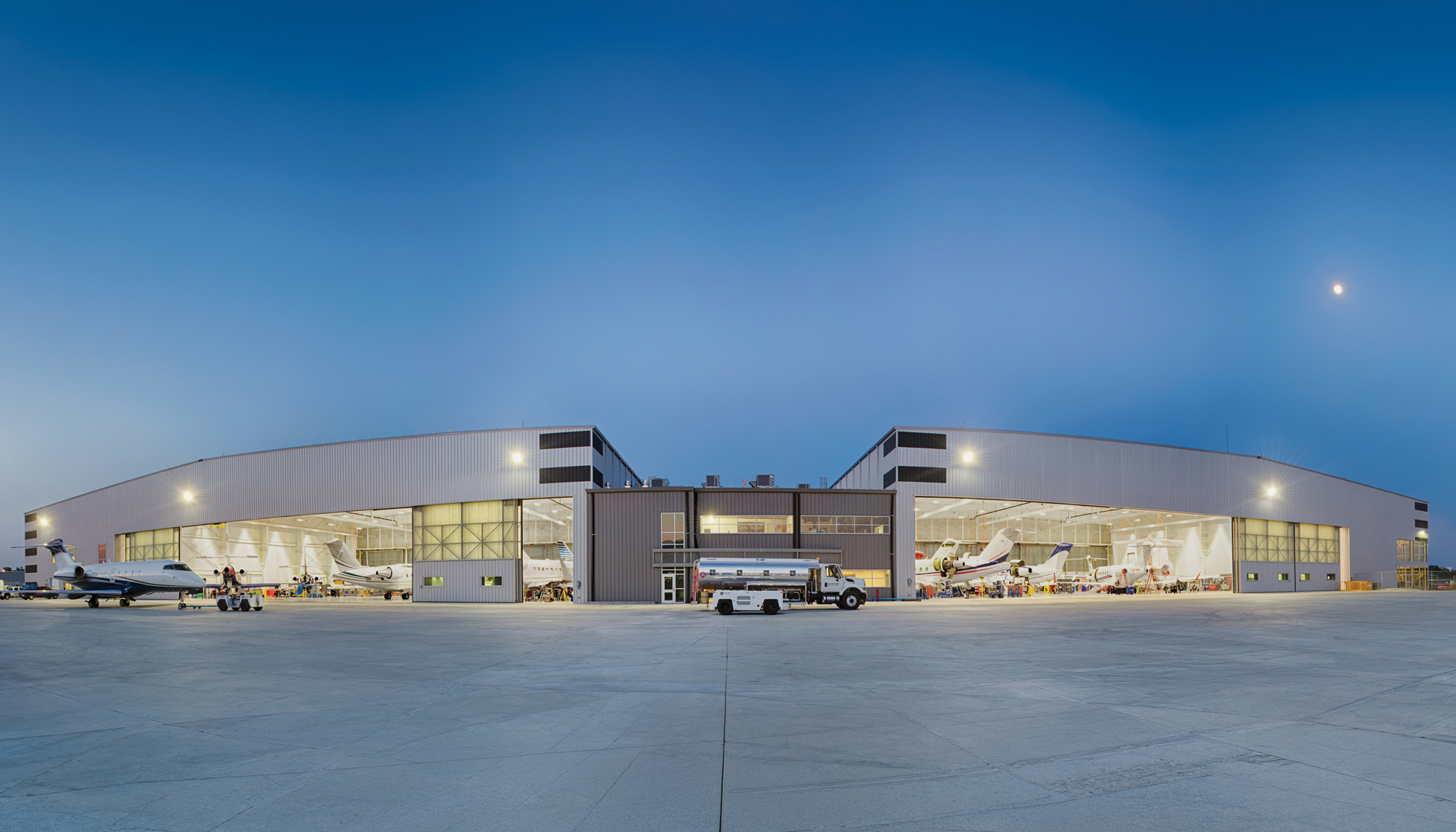 Wide exterior evening view of the Duncan Aviation Lincoln Maintenance Hangar featuring expansive clear-span aircraft service bays, integrated support facilities and coordinated aviation operations designed to accommodate larger aircraft and scalable maintenance capacity.