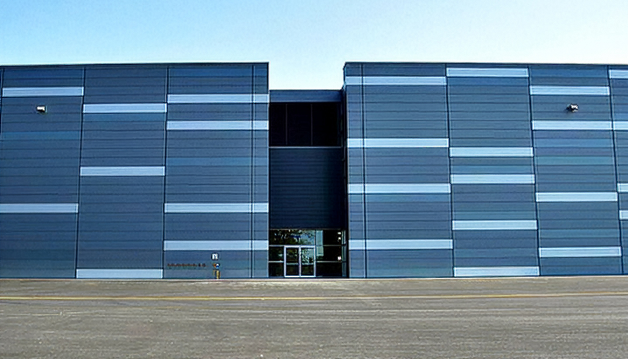 Exterior architectural view of the Dassault Falcon Jet – 14 Bay Hangar featuring coordinated aviation façade systems, expansive structural spans and integrated aircraft operations infrastructure designed to support high-capacity hangar performance and precise operational efficiency.