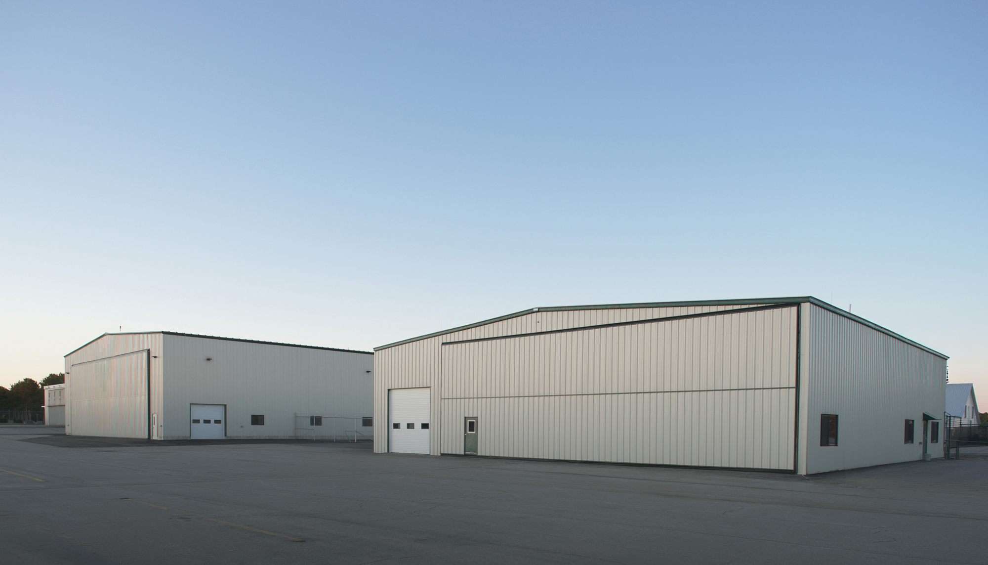 Exterior view of the Maine Instrument Flight Corporate Hangar complex featuring streamlined aircraft support buildings designed to maximize operational efficiency within a constrained aviation site.