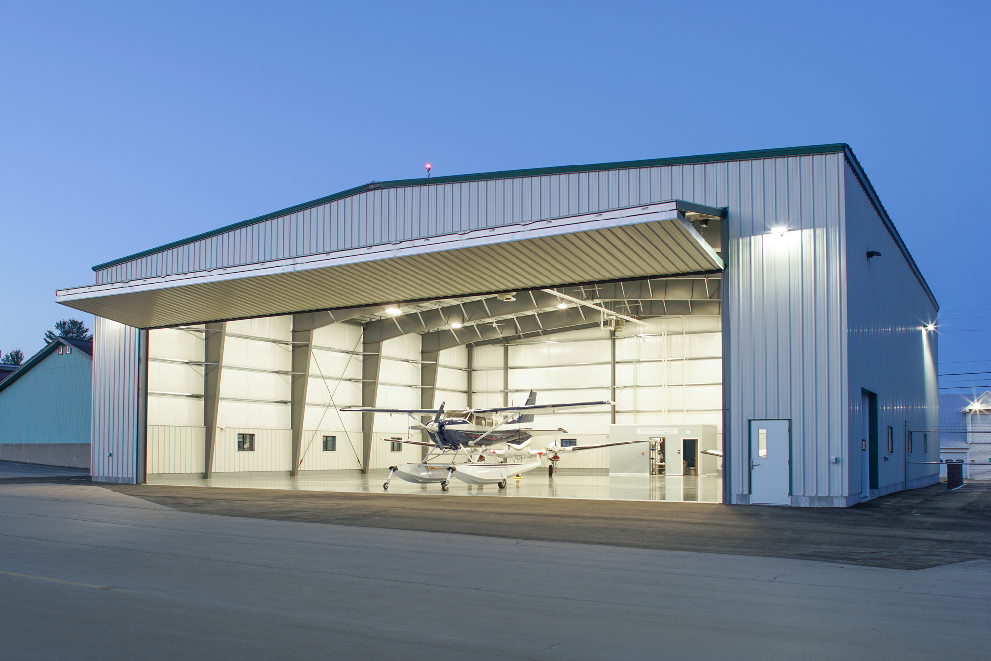 Aircraft positioned inside the Maine Instrument Flight Corporate Hangar featuring a large clear-span opening and coordinated structural design developed for efficient aircraft access on a constrained site.