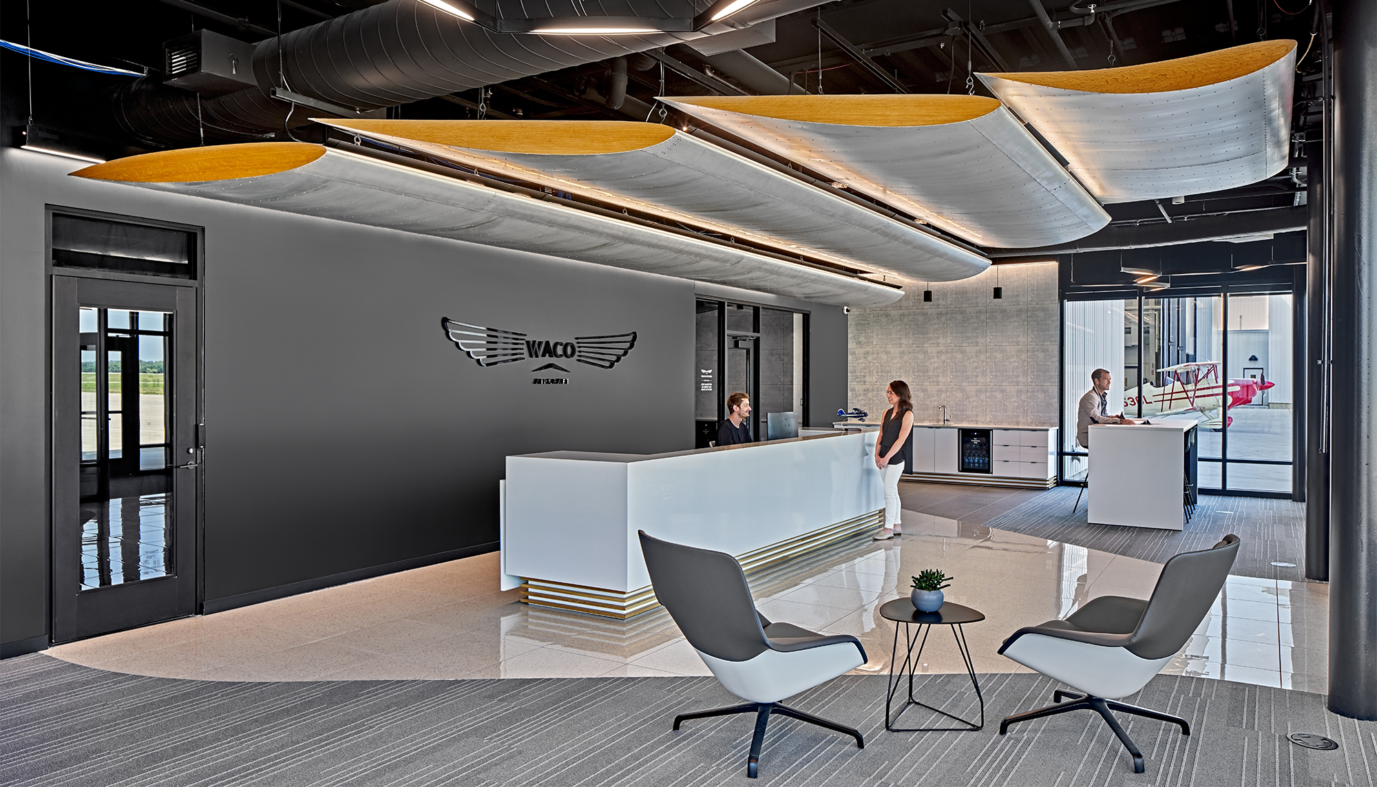 Interior reception area at the WACO Aircraft Corp. facility featuring integrated client-facing spaces, modern aviation branding and coordinated environments designed to support customer engagement alongside aircraft manufacturing operations.