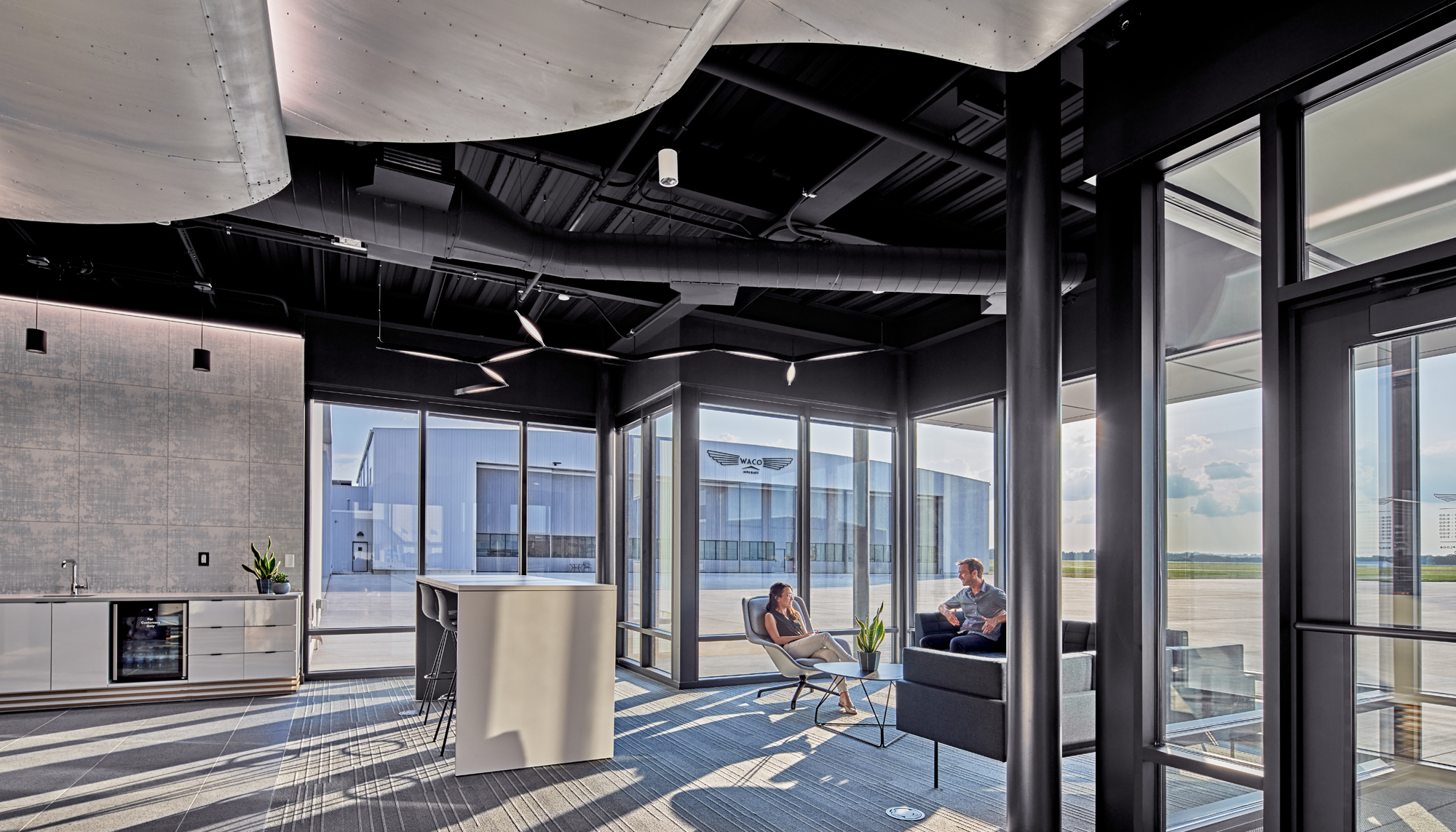 Interior lounge and client meeting space at the WACO Aircraft Corp. facility featuring integrated glazing, collaborative seating areas and coordinated architectural design developed to support aviation customer engagement and operational connectivity.