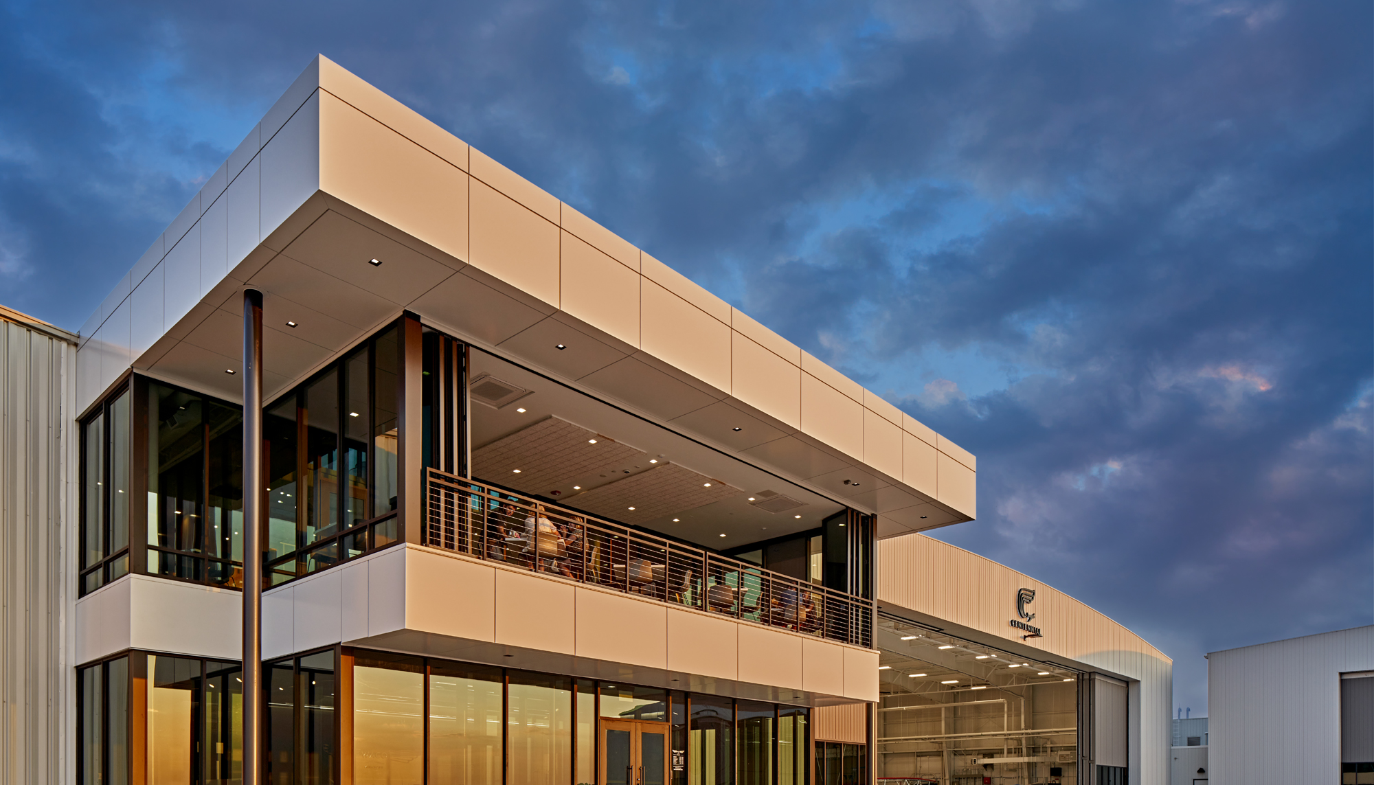 Exterior evening view of the WACO Aircraft Corp. facility featuring integrated client-facing spaces, expansive glazing and coordinated architectural design developed to support aviation manufacturing, customer engagement and phased campus growth.