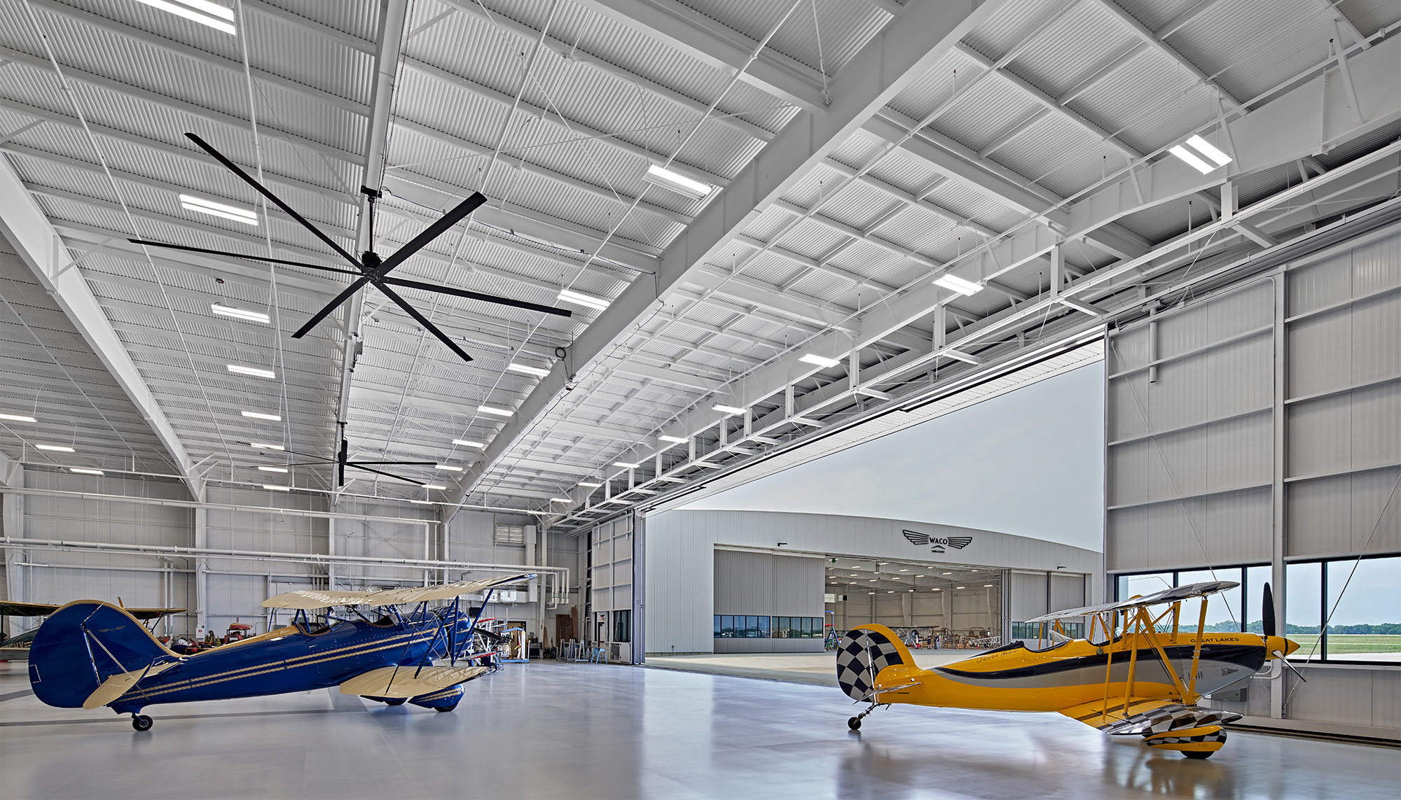 Interior aircraft hangar at the WACO Aircraft Corp. facility featuring clear-span operational space, integrated aviation support systems and coordinated manufacturing environments designed to support aircraft assembly, servicing and customer engagement.