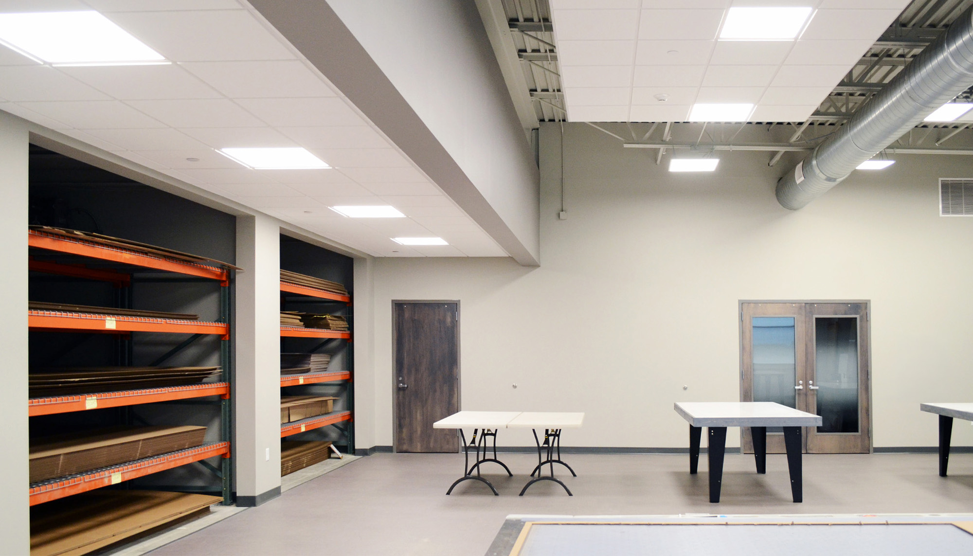 Industrial facility interior featuring material storage racks, fabrication workspace and steel building construction.