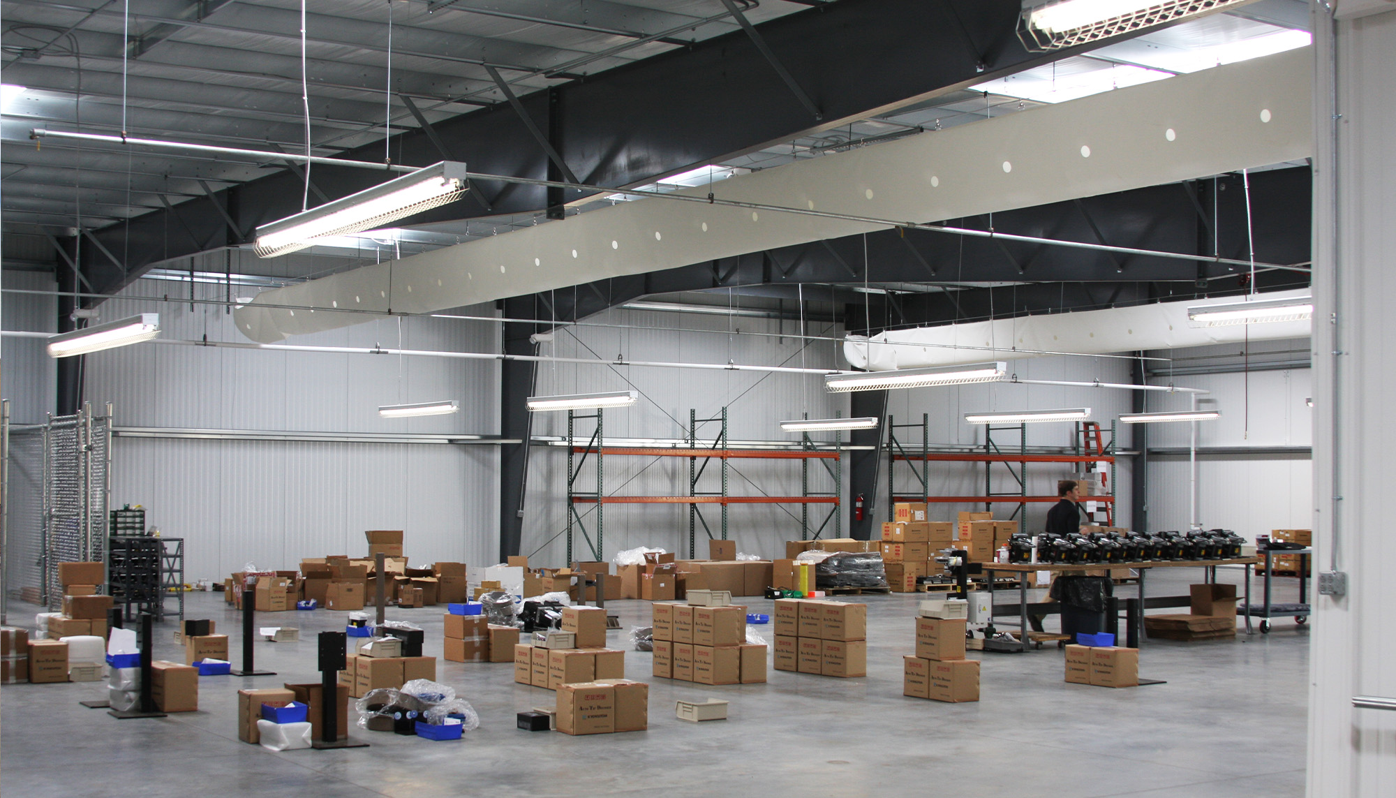 Industrial warehouse interior with structural steel framing, material staging area and distribution operations workspace.