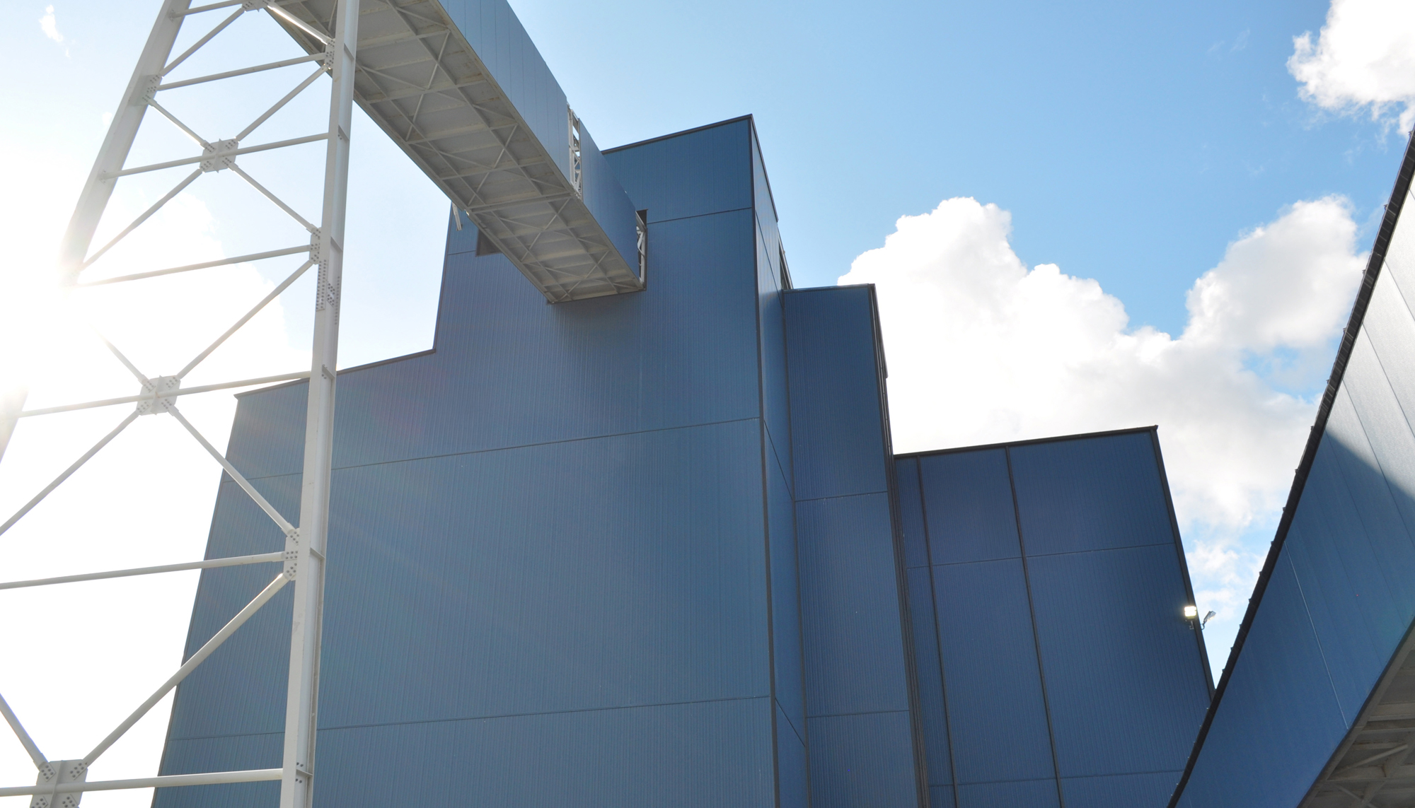 Industrial processing facility exterior at the GreenStone Gold Mines site featuring elevated material handling connections and insulated wall panels.