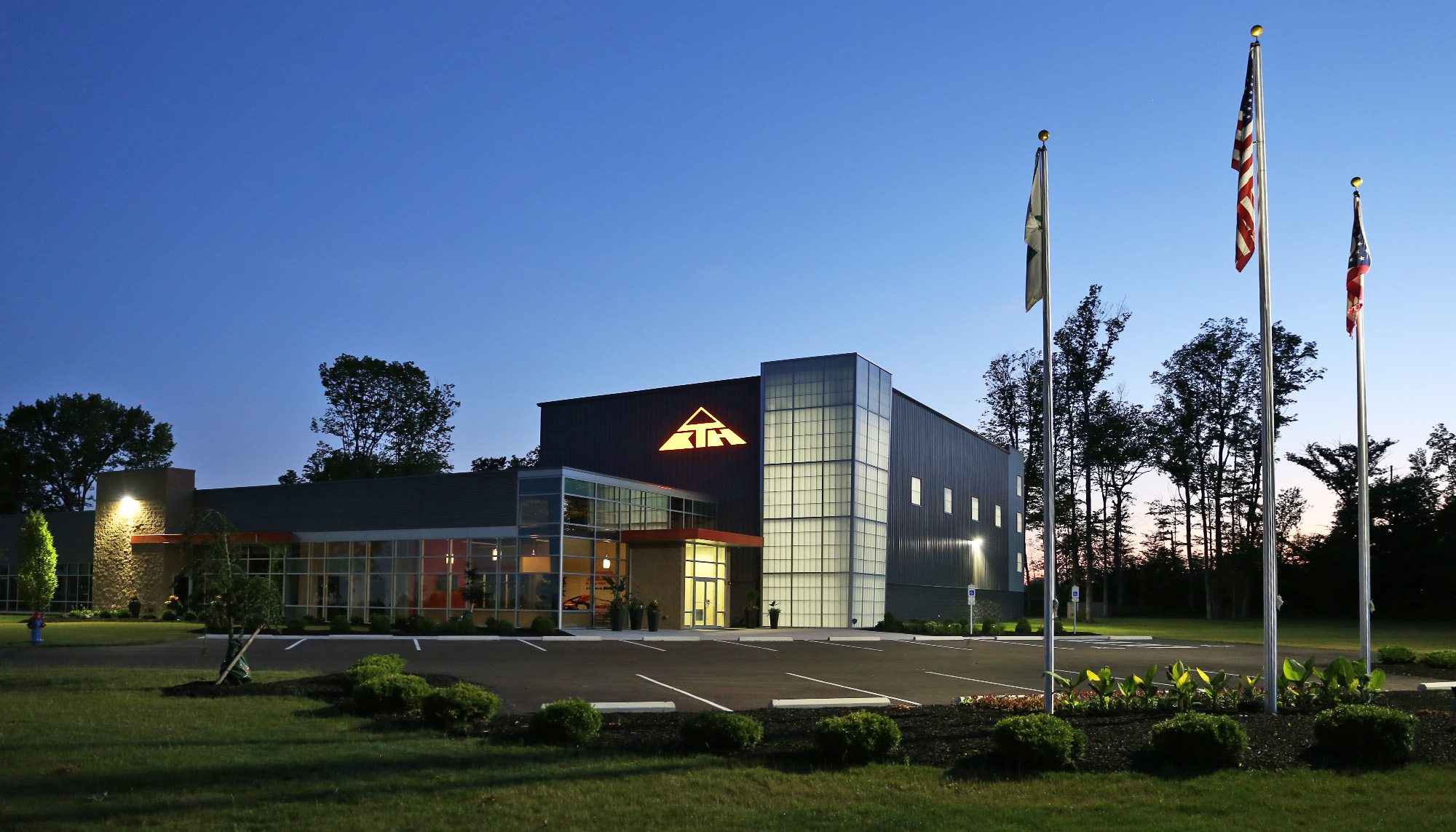 Commercial office building featuring architectural metal wall panels, curtain wall glazing and steel building construction at dusk.