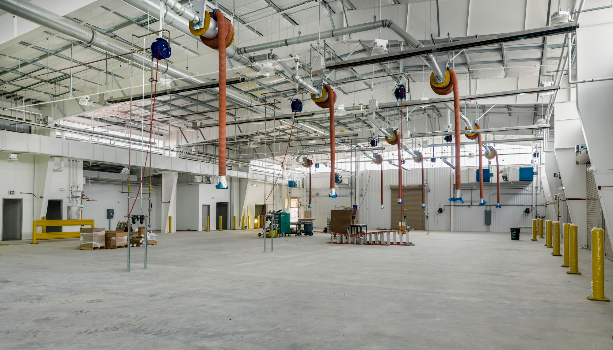 Interior maintenance space at the U.S. Navy Forklift Rework Facility featuring integrated overhead crane systems, open repair areas and coordinated operational zones designed to support equipment servicing and hands-on training.