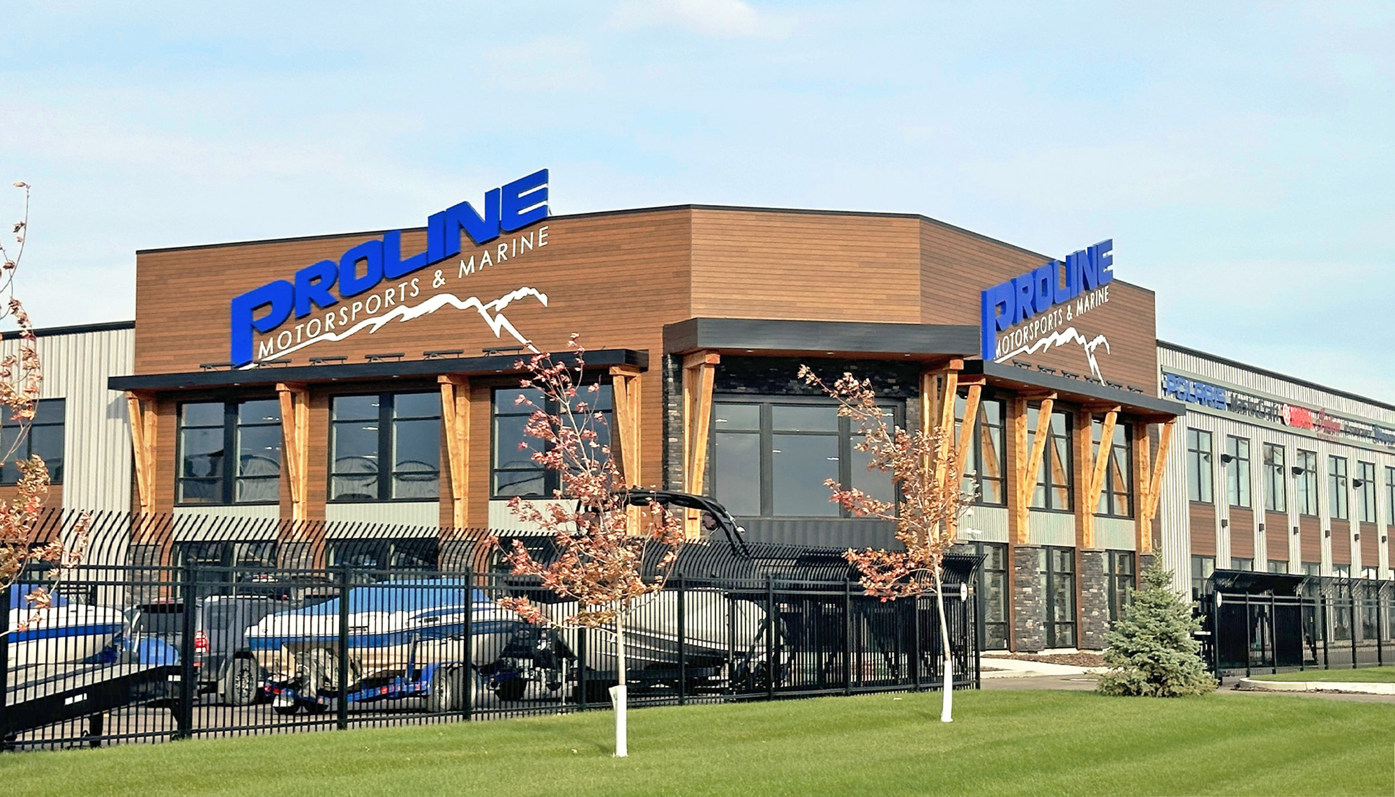 Corner view of Proline Motorsports & Marine featuring metal wall panels, timber accents, large windows and an outdoor boat storage area.