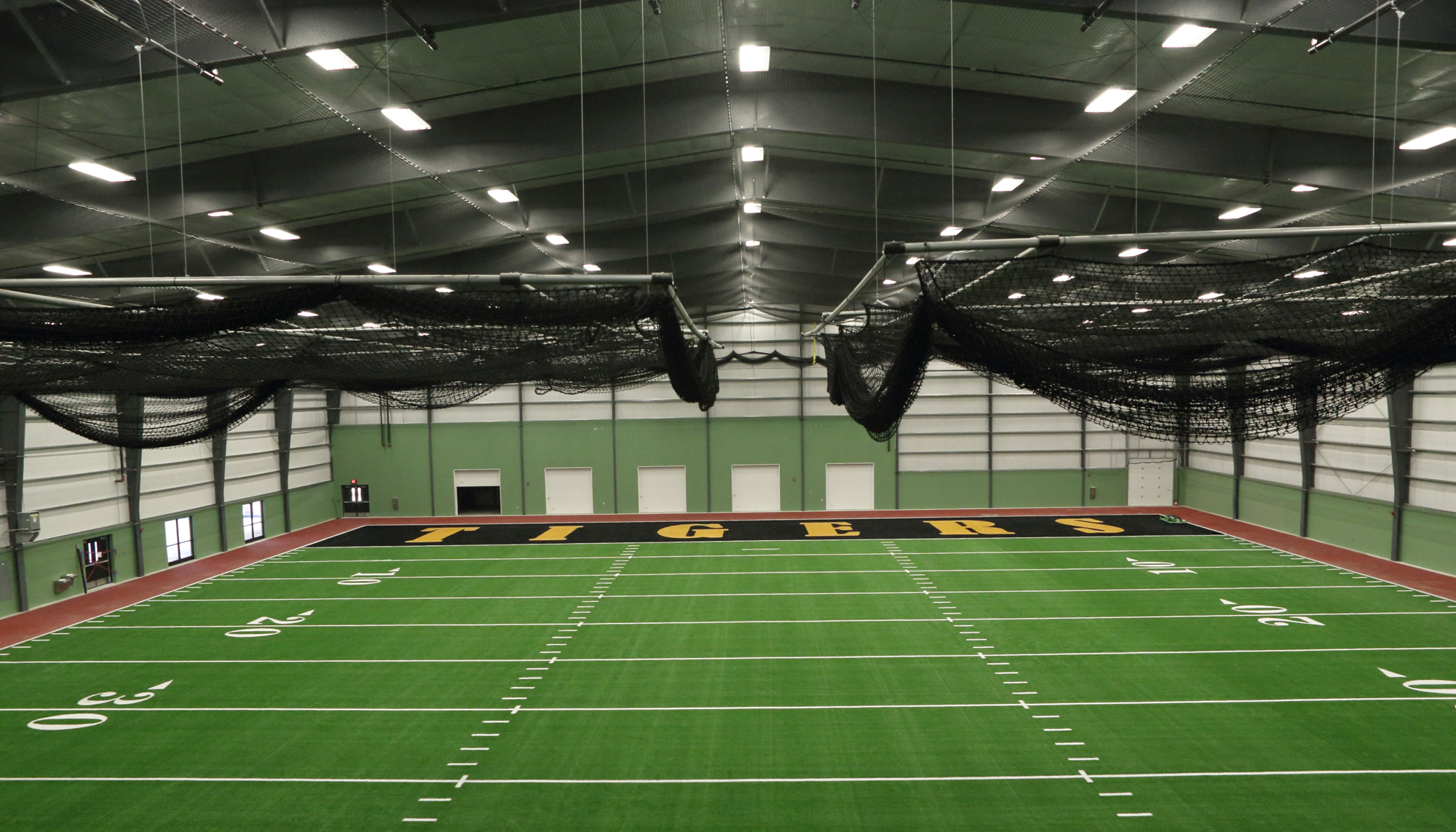Interior training field at the Fort Hays State University Indoor Practice Facility featuring clear-span construction and multi-sport turf space.