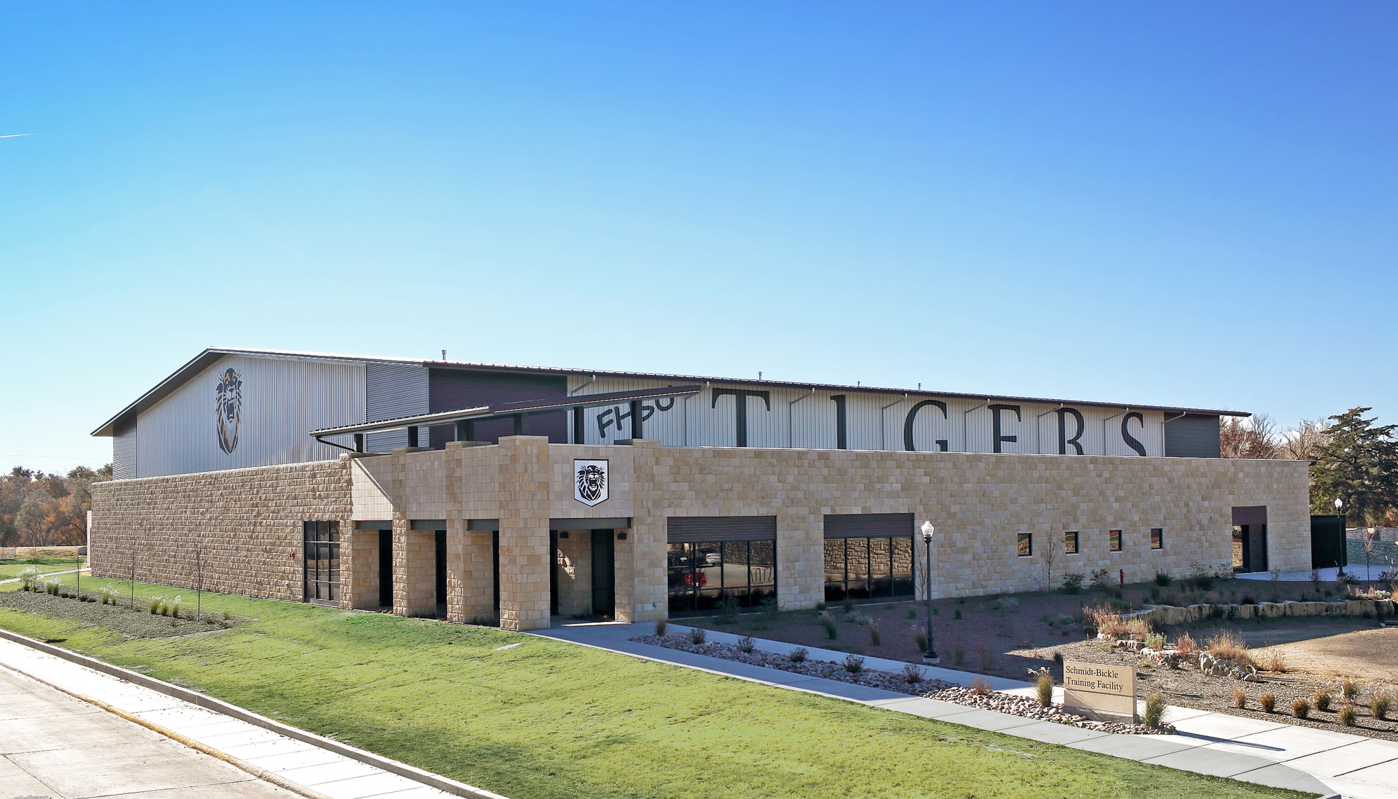 Exterior view of the Fort Hays State University Indoor Practice Facility featuring stone facade, covered entry and integrated campus design.