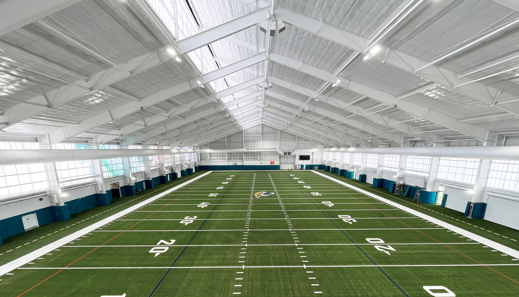 Indoor football training facility featuring clear span steel framing, artificial turf field and large-span athletic building construction.