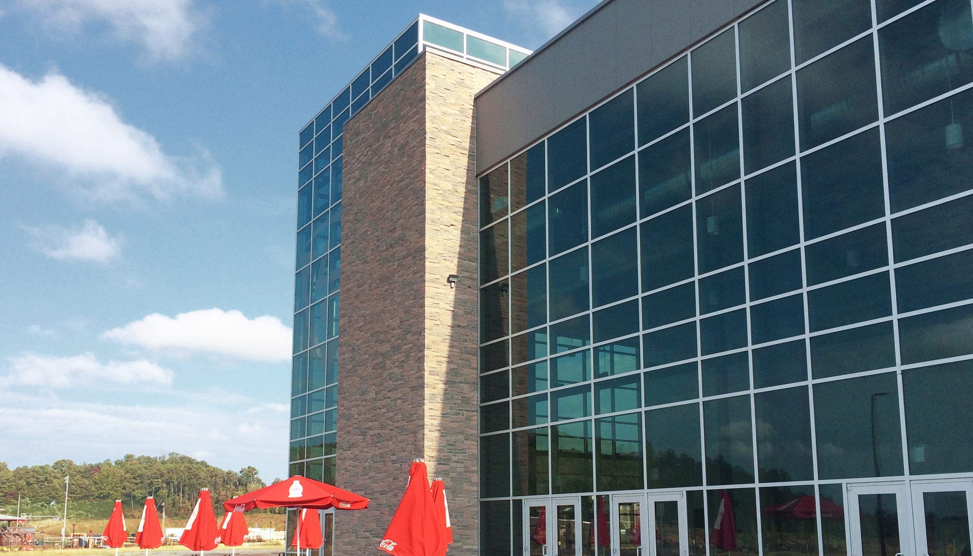 Glass entry façade of the LakePoint Sports Champions Center featuring expansive curtainwall glazing and integrated pedestrian access for a large-scale indoor athletic facility.